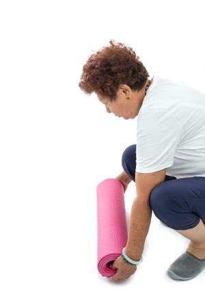 Senior hand's rolling pink yoga mat on white. copy space for textの写真素材