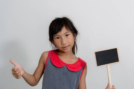 Cute Asian girl holding blank blackboards with gray background.の写真素材