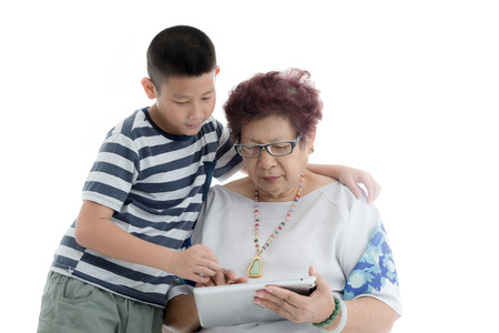 Asian senior woman and boy reading at book on white background.の写真素材