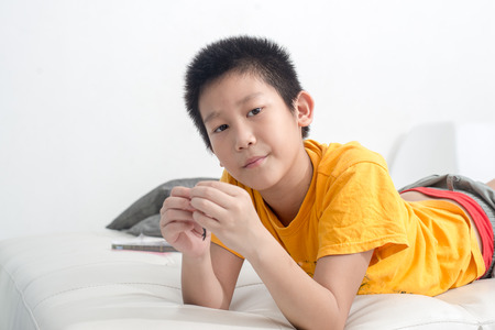 Asian boy playing clay on sofa at home.の写真素材