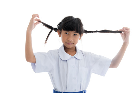 Asian child in uniform with pigtail on white background.の写真素材