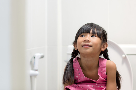 Asian girl sitting on toiletの写真素材