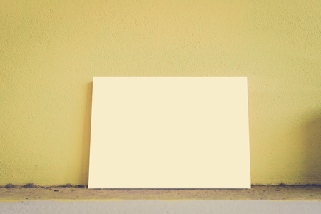 Mock up paper display on dirty and yellow wall in vintage style.の写真素材