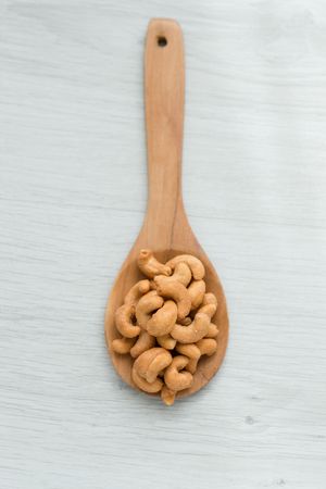 Salty cashew nuts in wood spoon on gray wooden tableの写真素材