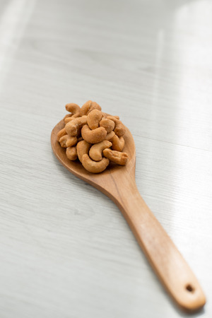Salty cashew nuts in wood spoon on gray wooden tableの写真素材