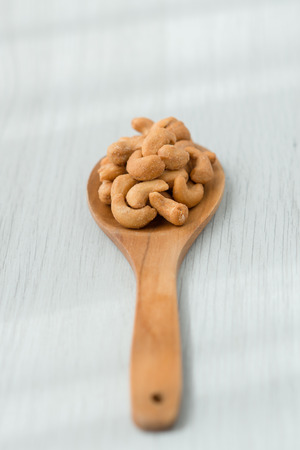Salty cashew nuts in wood spoon on gray wooden tableの写真素材