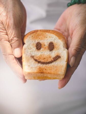 Senior Hand holding Happy toasted  with warm window light.の写真素材