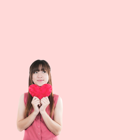 Happy Asian young woman holding small red heartの写真素材