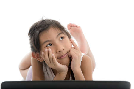 Asian child playing lapton on white floor.  Looking up something