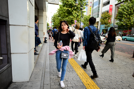 TOKYO, JAPAN - 07 OCTOBER 2016: Untitled Japanese teenager girl walking on a busy sidewalk, in the busy shopping district of Shinjuku, Tokyo.のeditorial素材
