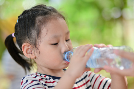 little girl drinks mineral waterの写真素材