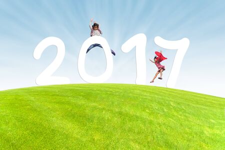 Girl jumping with Number 2017 on the green meadow with sun rayの写真素材