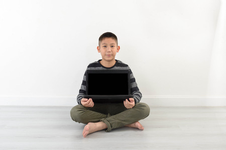Asian boy showing blank laptop at home.  Copyspace for mock up and text.の写真素材