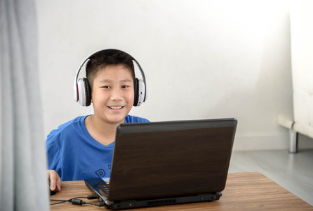 Young Asian boy using laptop technology at home.の写真素材