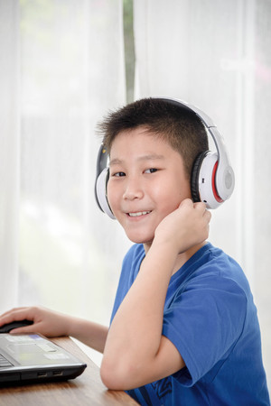 Young Asian boy using laptop technology at home.の写真素材