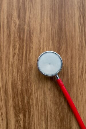 Red stethoscope on wooden background.の写真素材
