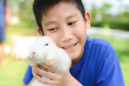 Asian kid smile and play with rabbit outdoor , selective focus