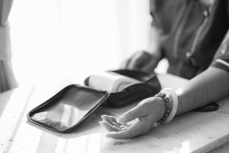 Asian senior woman checking blood pressure with window light, black and whiteの写真素材