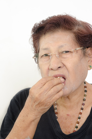 Asian senior woman eating popcorn while watching TV, at home.の写真素材
