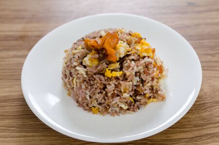 Fried brown rice with eggs and sausages on white dish.の写真素材