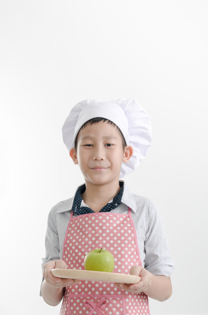 Asian boy wearing chef's hat holding green appleの写真素材