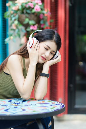 Beauty Woman wearing  braces and listening music in earphone on the street and sitting near the colorful wallの写真素材