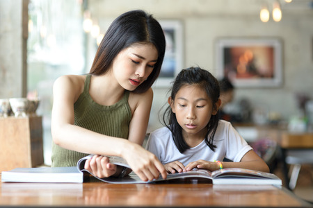 Beautyiful woman reading a book with her younger sister.の写真素材