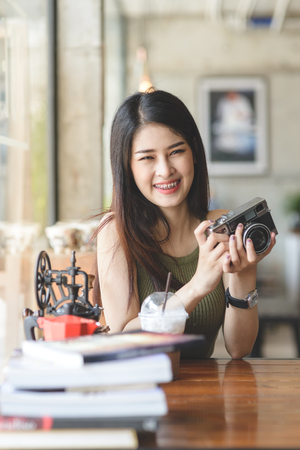 Happy Asian woman holding vintage camera in cafe, lifestyle concept.の写真素材