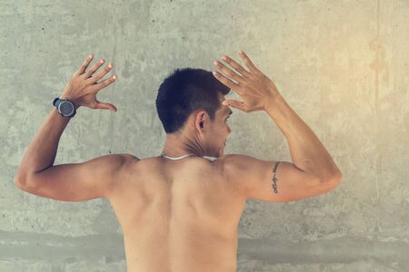 Back of sport man with sweat against cement wallの写真素材