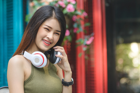 Happy Asian woman listening to music with color background outdoor.の写真素材