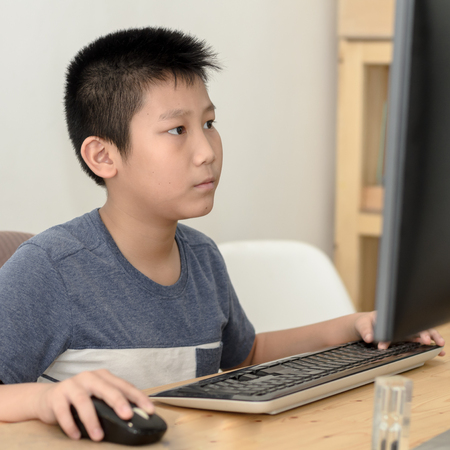 Happy Asian boy playing computer game at home.の写真素材