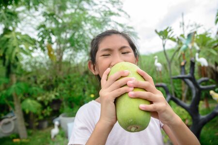 Happy girl showing papaya fruit in her hand after havestingの写真素材