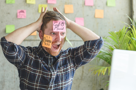 Stressed man with message on sticky notes over his face in office.の写真素材