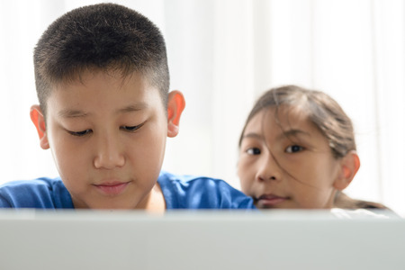Happy Asian boy and girl using tablet at home.