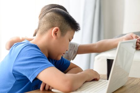 Happy Asian boy and girl using tablet at home.