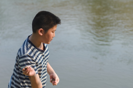 Asian boy throwing stone to water, outdoor lifestyle.の写真素材