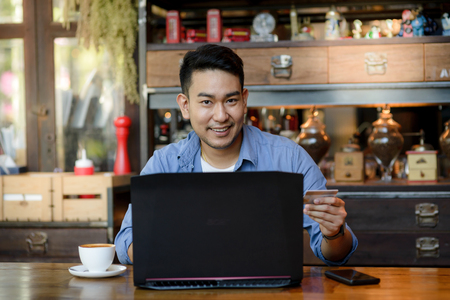 Man holds a credit card while entering data in laptopの写真素材