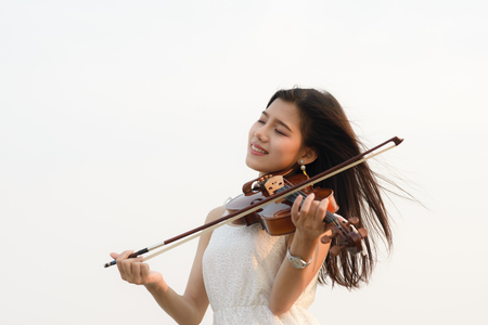 Happy woman playing violin on the beach.の写真素材