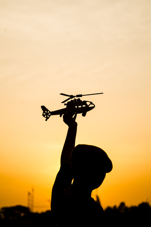 Silhouette boy playing  helicopter model with sun set.の写真素材
