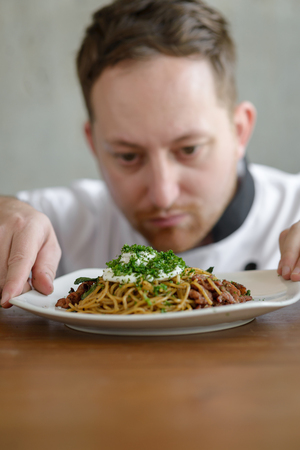Chef in in a restaurant or hotel kitchen, checking up his food and ready for service to the customer