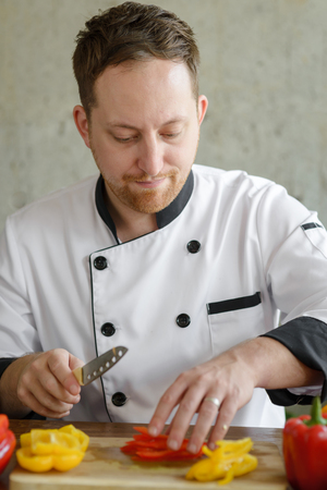 Professional chef chopping chili peppers for preparing food.の写真素材