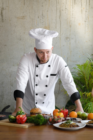 Professional chef looking at food and vegetable on table.