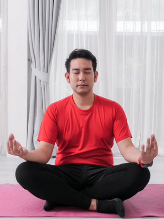 Asian man making meditation on floor at home.の写真素材