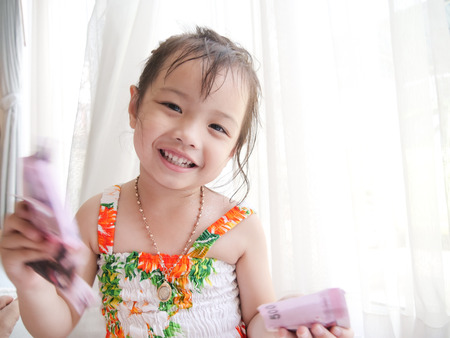 Happy Asian girl holding Thai money in her hands, saving concept.の写真素材