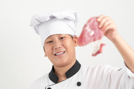 Asian preteen chef holding pork in his hand, food concept.の写真素材