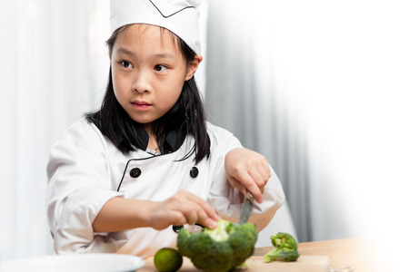 Young chef chopping broccoli on wooden board, lifestyle concept.の写真素材