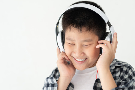 Motion blur happy Asian preteen boy using headphone on white background.の写真素材