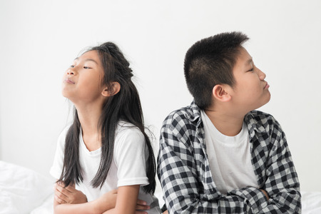 Arguing Asian preteen boy with his younger sister at home, lifestyle concept.の写真素材