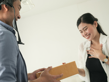 Asain woman receiving parcel from delivery man at the door.の写真素材