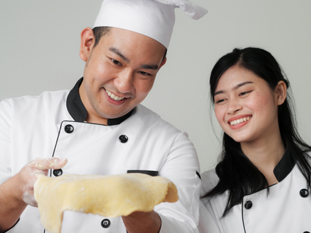 Asian chef holding dough in his hands,  showing to his helper, work lifestyle concept.の写真素材